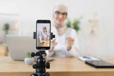 Başörtüsü takan Müslüman kadın akıllı telefondan tıpla ilgili video dersleri alıyor. Teknoloji ve eğitime odaklan. Genç yetişkin dijital içerik oluşturma ile meşgul.