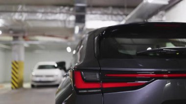 Modern arabanın arka lambaları yeraltı otoparkında, şık tasarım ve kentsel çevre sergileniyor. Otomotiv endüstrisi ve modern yaşam tarzı kavramları için ideal.