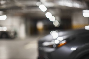 Loş yeraltı otoparkındaki arabayı gösteren soyut bulanık görüntü gizem ve modern şehir hayatını aktarıyor..