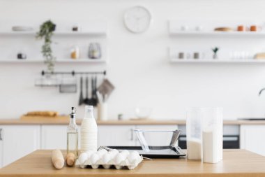 Malzemeler modern bir iç mekanda mutfak tezgahına düzgünce dizilmiş, pişirmeye hazır. Minimalist tasarım, yumuşak nötr tonlarla örgütlenmeyi ve işlevselliği teşvik eder.