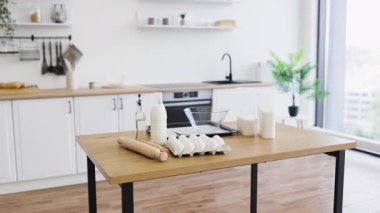Sofrada yumurta, süt ve un gibi minimalist dekorları ve fırınlama gereksinimlerini barındıran parlak çağdaş mutfak, basitliği ve pişirme veya pişirmeye hazır olmayı vurguluyor.