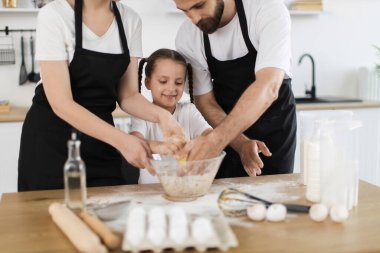 Üç kişilik beyaz bir aile mutfakta yemek pişiriyor, aralarında genç bir kız var, hamur yoğuruyorlar, bağ ve takım çalışması sergiliyorlar. Aileyi, yemeği, eğlenceyi, birlikteliği ve aşçılık yaratıcılığını yakalar.