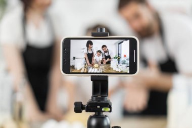 Yetişkin ve çocuk aşçı blogculardan oluşan beyaz bir aile ev yapımı yemek pişirme dersi videosu için hamur yoğuruyorlar..