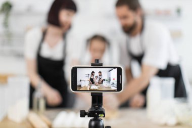 Çocuklu Kafkasyalı yetişkinler, evdeki enerjik fotoğraf oturumunda bloglar için yemek içeriği oluşturuyorlar.