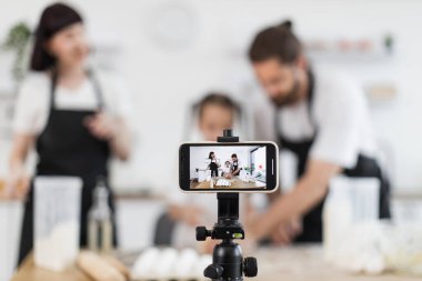 Modern mutfakta, dans etmek ve hamur yoğurmak da dahil olmak üzere yemek pişirme aktivitelerini bloglayan beyaz bir aile. Akıllı telefondan çekilen video eğlence, yaratıcılık, takım çalışması.