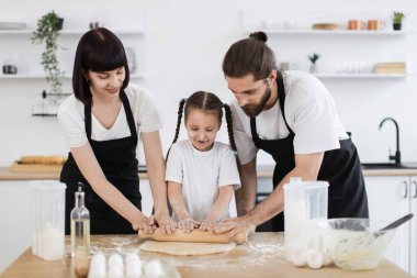 Kafkas ailesi, ebeveynler ve genç kız dahil, mutfak tezgahında hamuru sararken kaynaşıyorlar.