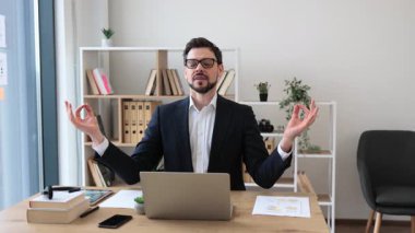 İş kıyafetleri içinde genç bir adam masa başında oturmuş, iş molası sırasında meditasyon yapıyordu. Sahne, işyerinin sağlığını, rahatlığını, farkındalığını vurguluyor. Kitap rafları olan ofis ortamı görünür bitki koltuğu