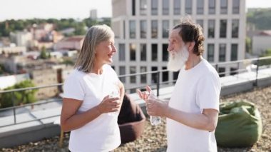 Üst düzey erkek ve kadın güneş ışığı altında açık havada egzersiz yaptıktan sonra çatıda iç çamaşırı giyiyorlar..