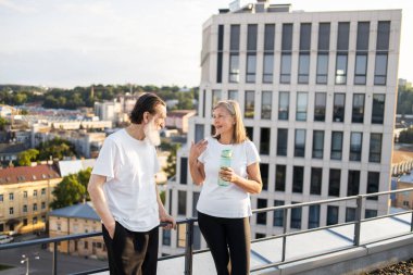 Aktif yaşlı erkek ve kadın şehir terasında çalıştıktan sonra bir anlığına paylaşıyorlar.