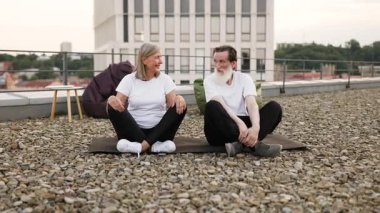 Yaşlı bir çift çatıda meditasyon yapıyor. Lotus 'ta oturan orta yaşlı erkek ve kadın, farkındalığı ve rahatlığı teşvik ediyor. Huzurlu ortam huzuru ön plana çıkarır.