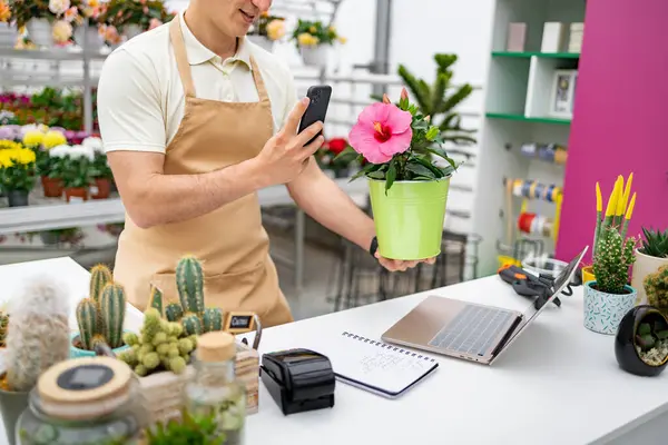 Çiçekçi, çiçek açan bir çiçeğin resmini çeker. Satılık olduğunu belgelemek için..