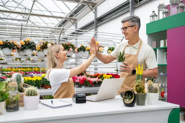 Beyaz tenli bir çiçekçi ve bir müşteri satıştan sonra beşlik çakıyor, mutlu bir jest..