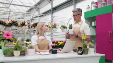 Beyaz tenli bir çiçekçi ve bir müşteri satıştan sonra beşlik çakıyor, mutlu bir jest..