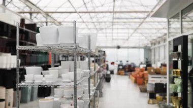 Bir fabrika dükkanının raflarında çeşitli şekil ve boyutlarda çiçek saksıları sergileniyor..