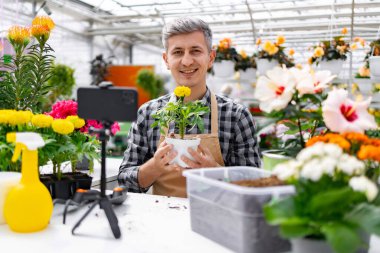 Bahçe merkezinde bir adam elinde saksı bitkisi tutarken video kaydediyormuş..