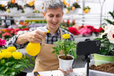 Çiçekçide çalışan bir adam bir bitkiyi sularken telefonuyla özel ders çekiyordu. İnternette öğretmenlik yapıyordu..
