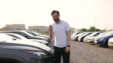 Bir adam yeni araba alımını kutluyor, araba galerisinin anahtarlarını elinde tutuyor..