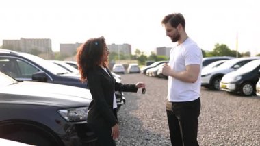 Kadın bir araba satıcısı başarılı bir alışverişin ardından anahtarları erkek bir müşteriye verir ve anlaşmayı sağlamak için el sıkışır..