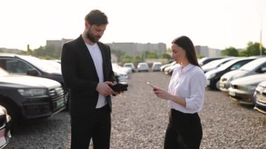 Erkek bir araba satıcısı, güneşli bir günde araba alan bir kadına anahtarları verir..