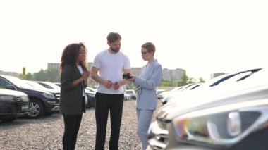 Bir çift, araba galerisinde bir araba için kredi kartı kullanıyor. Araba galerisindeki bir satıcının da yardımıyla..