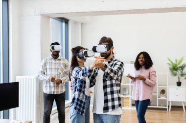 Young diverse adults in modern office using virtual reality headsets engaging in teamwork activity. Innovative approach to technology enhancing creativity and collaboration.