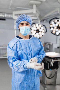 A surgeon wearing a mask and surgical gown prepares for an operation in a sterile operating room.
