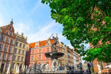 Polonya 'nın Gdansk şehrinde Neptün çeşmesi ve renkli binalarla dolu bir cadde.