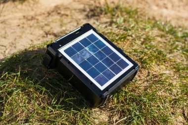 Güneş paneli ve yeşil çimlerin üzerindeki pil. Doğa ve turizm için taşınabilir istasyon. Cihazları şarj etmek için ekolojik enerji tipi.