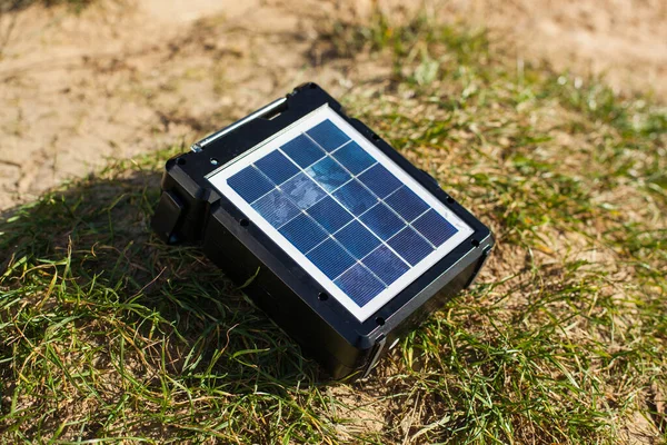 Solar panel together with battery on green grass. Portable portable station for nature and tourism. Ecological type of energy for charging gadgets.