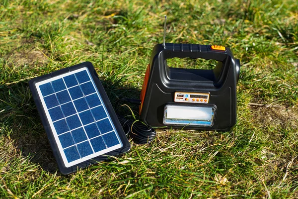 stock image A portable charging station with a flashlight is charged from a solar panel in nature. The battery for charging gadgets is charged in sunny weather.