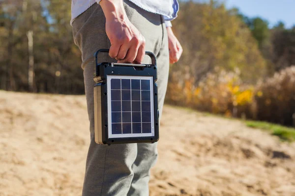 一个人拿着一个便携式太阳能电池板充电设备 这种型号的电池是为大自然准备的 图库照片