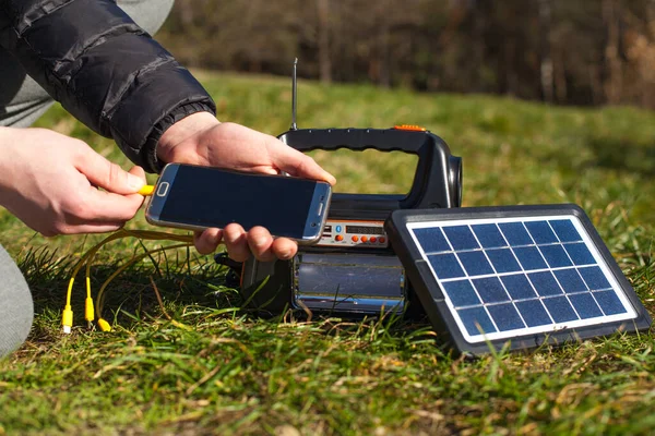 一个男人在充电器上装了一个太阳能充电器电话 关于用于远足 旅游和旅行的生态能源的便携式电站 免版税图库照片