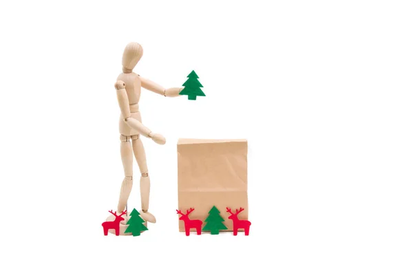 Wooden dummy man and paper bag, christmas preparation on isolated white background. Christmas deer and tree.