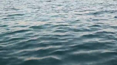 Sahilde altın bir günbatımı - köpüklü dalgaların yavaş çekimi. Kızıl Deniz 'in dalgaları kumlu kumsala doğru gün ışığında süzülüyor. Güneş ışığının altında.