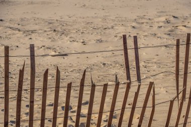 Kum tepeciğinde bir çit. Çapraz çizgiler ve güneş ışığı gölgeler oluşturur..