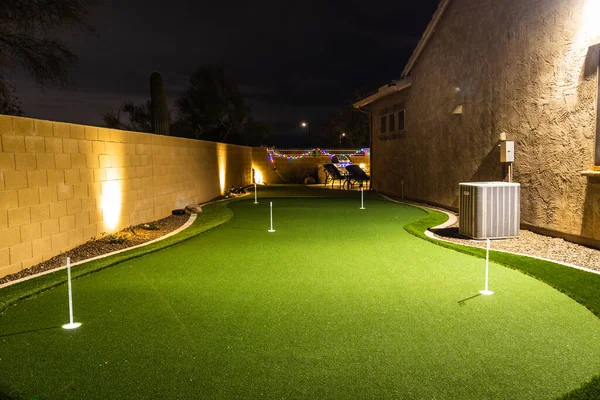 Nighttime image of a personal home putting green with illuminated holes.