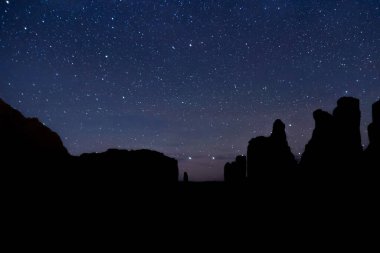 The night sky over the desert rock formations of Utah in Arches National Park.