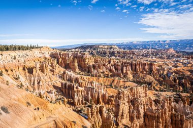 Bryce Canyon accented in freshly fallen snow and distant mountains and brilliantly colored orange cliffs.