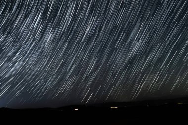 Hareket eden Evren. Gece gökyüzü merdivenleri uzak arabalardan gelen ışık çizgileriyle.