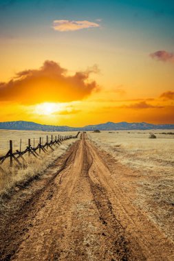 A lonely dirt road through the grasslands along the border between the United States and Mexico in Arizona.