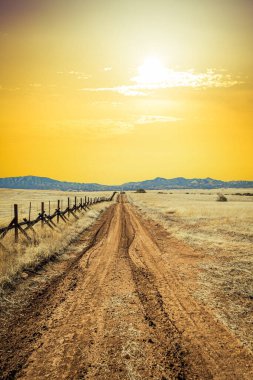 A lonely dirt road through the grasslands along the border between the United States and Mexico in Arizona.
