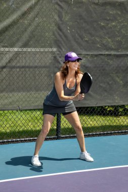 A pickleball player prepares for a return of serve on a suburban pickleball court during summer.
