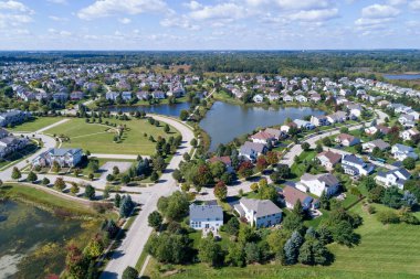 Aerial view of a neighborhood housing development in suburban Chicago during summer with pond and play area.