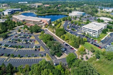 Otoparkı ve göleti olan banliyö ofis parkının havadan görüntüsü..