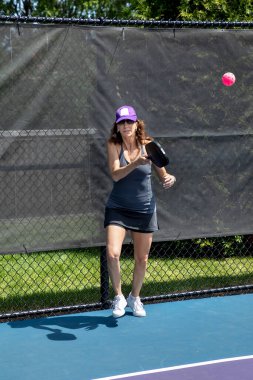 A pickleball player returns a serve on a suburban pickleball court during summer.