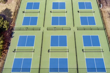 Baharın başında banliyö parkındaki bir oyun parkının yanında mavi ve yeşil kortlu bir yankesicilik kompleksinin hava manzarası.