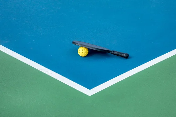 白い線で青と緑の裁判所にピックルボールパドルと黄色のボールの眺め ストックフォト
