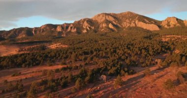 Soft light bathes the landscape and mountains of Bear Peak and Green Mountain just after sunrise in the city of Boulder, Colorado in winter.
