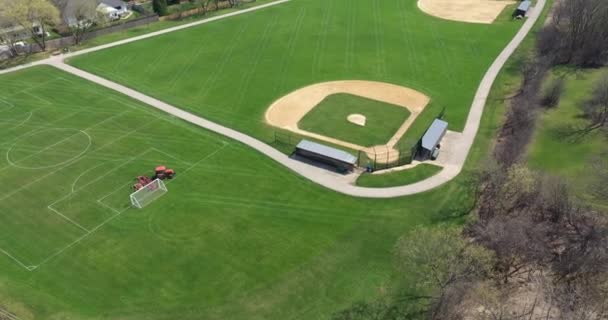 大規模な郊外公園内の野球場 サッカー場の空中風景で 早春には運動場の芝刈り機が草をつついている — ストック動画