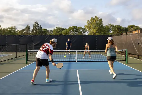 当他和他的搭档接近球网时 一名男子泡菜手准备击球 以对付对手 图库图片